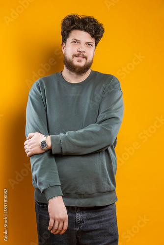 Youth Lifestyle. Caucasian Young Tranquil Brunette Handsome Man in Green Shirt Sweatshirt As Casual Clothes Looking Straight Isolated on Plain Light Yellow Background