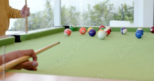 Player is placing cue ball, aligning stick and striking to break colored balls on pool table