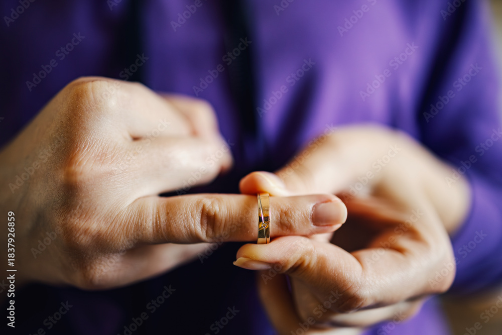 Obraz premium Person removing wedding ring symbolizing divorce and separation