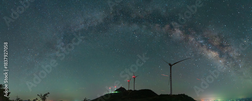 Obraz na plátně Silhouette of wind turbines under a starry night sky with the milky way visible,