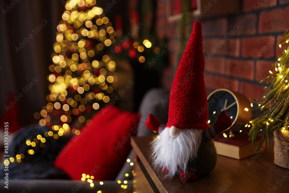 Fototapeta premium Funny Christmas gnome on cabinet in decorated room, closeup. Space for text