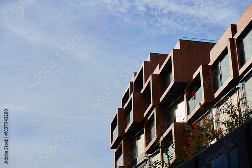 Modern building facade with geometric metal panels and large windows under clear sky. Concept of contemporary architecture, urban exterior and commercial property design.