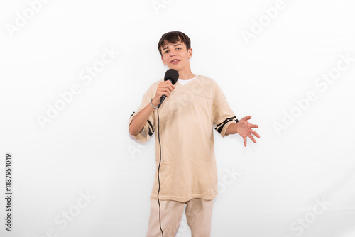 young casual dressed Generation Z influencer white male host model teenage boy with microphone for singing, presenting and interviewing for social media channel. plain background studio setting