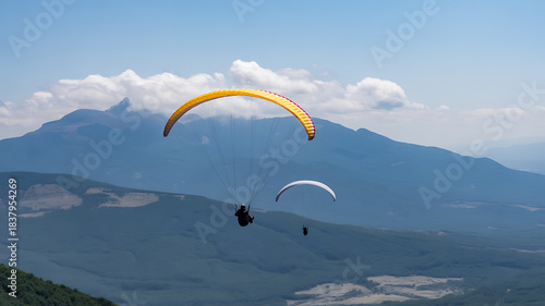 Paragliders Soaring Over a Mountainous Landscape Under a Cloudy Sky paragliding flying