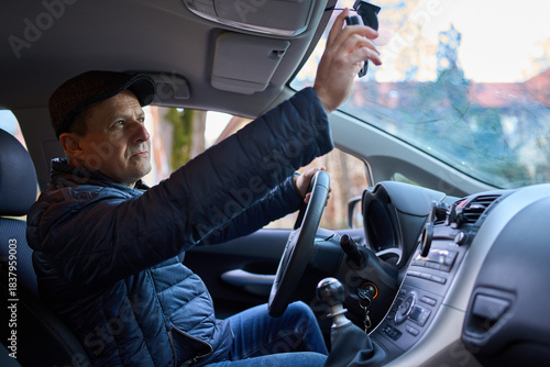 Man adjusting rearview mirror in car