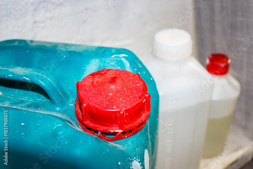 Wallpaper Mural Vibrant red screw cap topping a dusty teal plastic container, with blurred white chemical bottles in the background setting a work-in-progress mood Torontodigital.ca