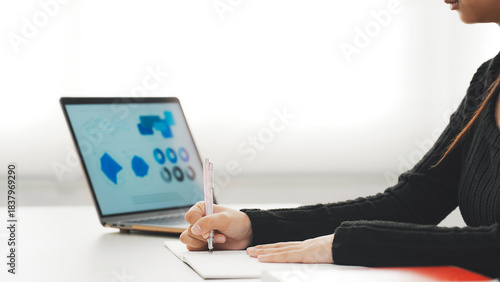 デスクでノートパソコンを見ながら勉強する女性