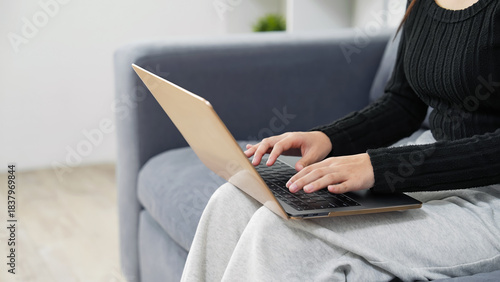 部屋でノートパソコンを使う女性