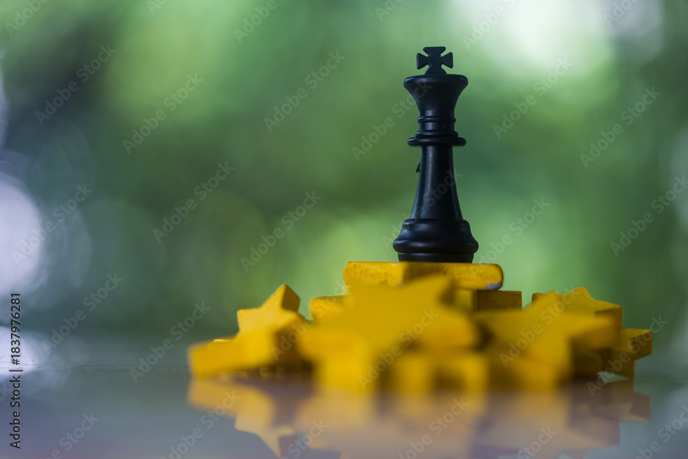 Obraz premium King chess piece remaining upright on a pile of yellow stars, representing business strategy and competition, symbolizing triumph, strategy, and overcoming challenges