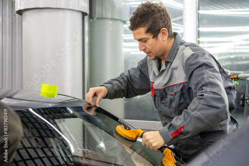 Automobile special workers replacing windscreen or windshield of a car in auto service station garage. Glass of the car, removed with the help of professional suction cups. The process of car repair. 