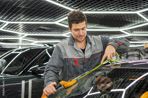 Automobile special workers replacing windscreen or windshield of a car in auto service station garage. Glass of the car, removed with the help of professional suction cups. The process of car repair. 