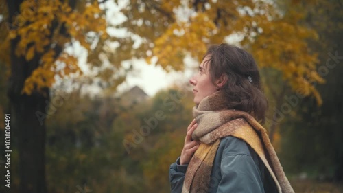 [yellow leaves, tree crowns] Beautiful Slavic woman in a scarf joyfully reflecting in a picturesque autumn landscape filled with vibrant foliage and serene moments of self-discovery.