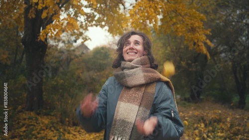 Yellow Leaves, Tree Canopies, Smile: Beautiful Young Slavic Woman in Scarf Joyfully Engaging with Autumn Nature while Juggling Leaves and Reflecting on Life