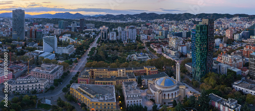 Dawn aerial panorama of central Tirana over Skanderbeg Square surrounded by city landmarks.
