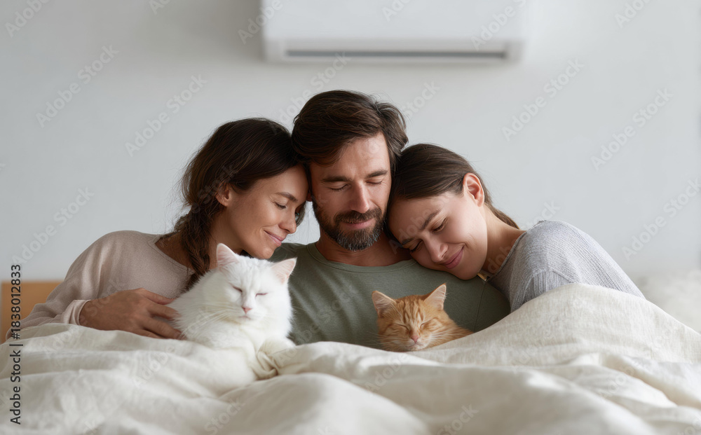 Fototapeta premium Affectionate trio including man woman and friend cuddling in bed with two cats while feeling cozy peaceful and happy relaxing under blanket enjoying warm comfortable morning together in bedroom