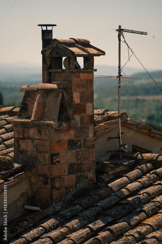 Fototapeta premium chimney silhouettes under sunset light, weathered chimney and village scene in warm late afternoon glow