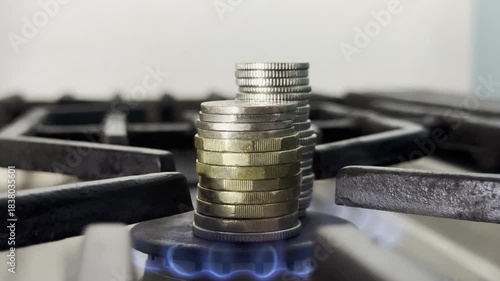 Closeup of stacked money coins burning on a cooker hob. Concept of domestic gas energy cost, or money to burn.