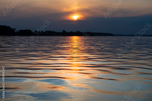 Sunset and its reflection in the water and waves of the reservoir