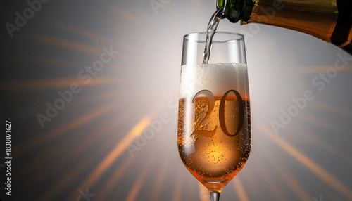  Glass engraved with the number 20. Champagne bottle fills the glass with alcohol. Celebrating milestone, anniversary or birthday