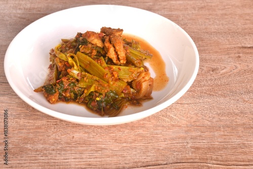 spicy stir fried Thai morning glory with slice fat pork belly in curry sauce on plate 