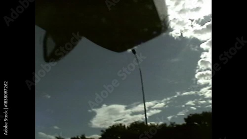 Man in driver's seat captured in dim light with grainy VHS-style visual and reflections