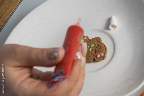 Woman decorating gingerbread cookie with gaze