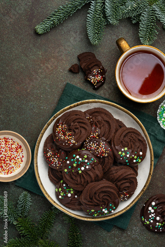 Chocolate Christmas sable cookies decorated with chocolate and sprinkles on a plate. Top view.