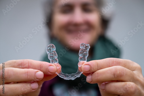 Foto Senior woman smiling while holding an aligner for orthodontic treatment