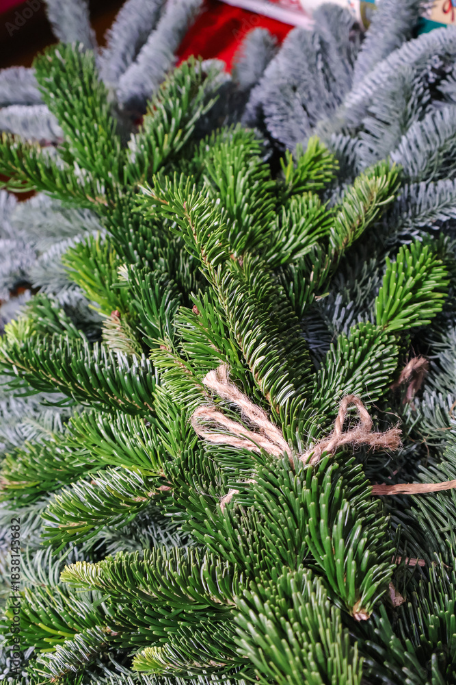 Fototapeta premium Green Christmas tree branches with ornaments and lights. Seasonal close-up for holiday backgrounds, branding and product placement. Winter background ideal for Christmas themes mood and ornament.