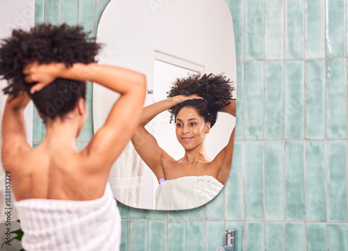 Woman With Natural Hair Ties Up In Bathroom Mirror To Start Her Morning Self-Care Routine