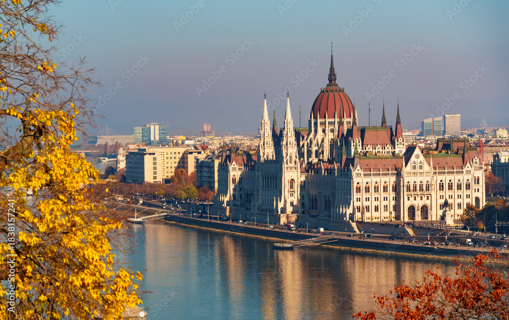 Fototapeta premium Budapest cityscape, panoramic view of city and Danube River, Parliament building and beautiful architecture in autumn season, trees, branches and yellow leaves in foreground