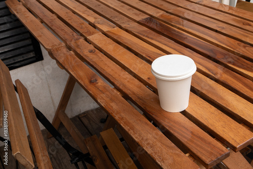 Coffee to go on wooden table, outdoors cafe. Takeaway white paper eco coffee cup