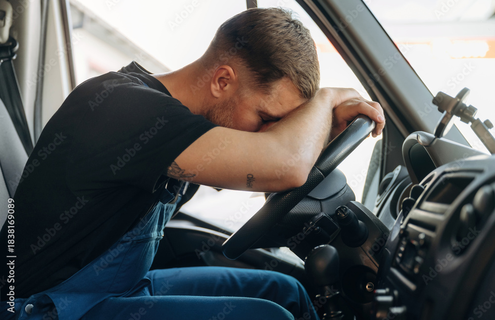 Fototapeta premium Tired, sleeping on the steering wheel. Inside of the bus with delivery service man in uniform
