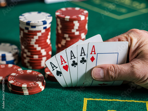 Ultimate poker hand showing four aces ready to win big next to towering stacks of casino chips