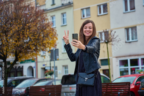 Woman taking selfie with smartphone on city street