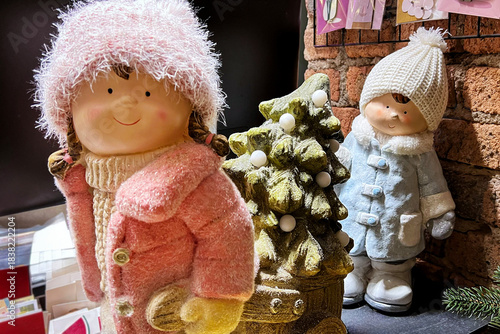 Holiday decor with dolls in winter outfits, a Christmas tree, and a sleigh at a flower shop. Christmas holiday concept.