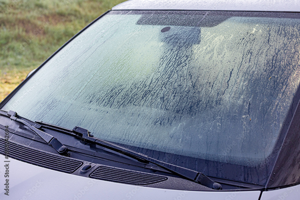 Obraz premium Car windshield covered in thick ice and frost on a cold winter morning, needing scraping before driving