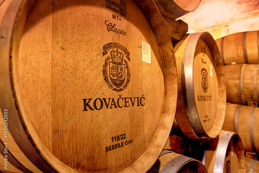 Obraz premium 31 August 2025, Irig, Serbia: Wooden barrels aging wine in a dim cellar, showing stacks of casks for fermentation in Kovacevic winery