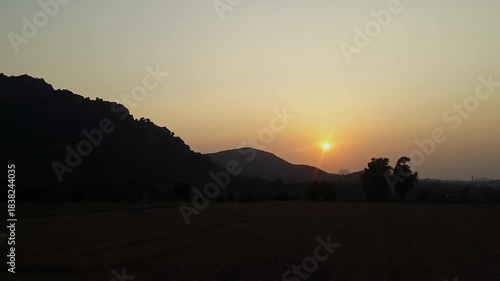 An epic view of a beautiful sunrise over the hills, in front of farmland in rural village