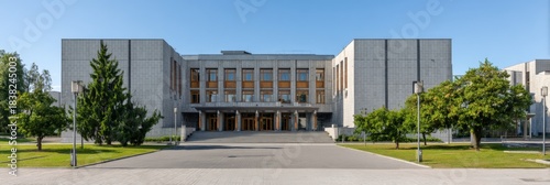 Modern concrete government building with front entrance and nearby green trees