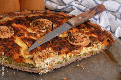 Tarte salée au fromage de chèvre et aux légumes dans un plat avec un couteau en gros plan