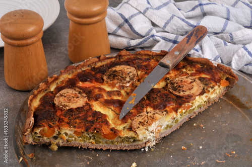 Tarte salée au fromage de chèvre et aux légumes dans un plat avec un couteau en gros plan