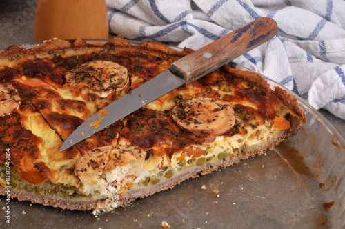Tarte salée au fromage de chèvre et aux légumes dans un plat avec un couteau en gros plan