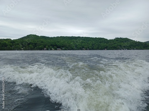 Φωτογραφία View from the back of a motorboat churning up lake water on a cloudy day