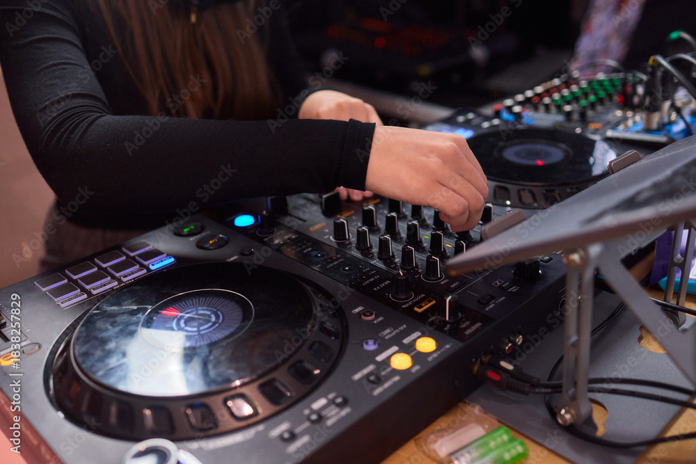Naklejka premium DJ setup overview, Energetic club DJ performing with digital controller in action, Content creator mixing music live using digital turntables under vibrant stage lights