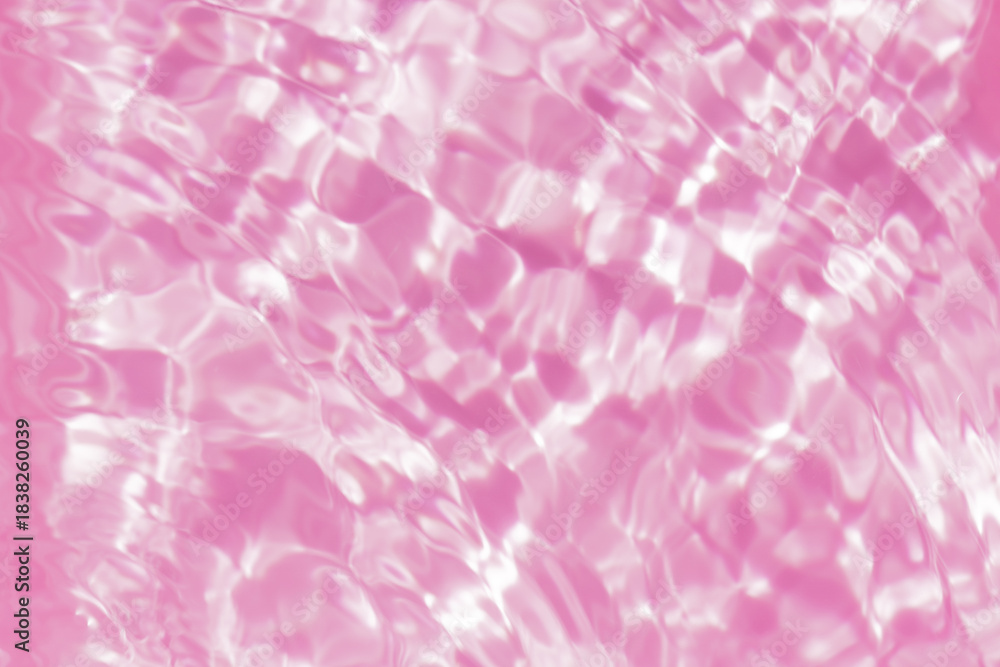 Fototapeta premium Close-up of calm pink clear water surface with water spray and bubbles. Trendy abstract summer nature background. Coral waves in sunlight