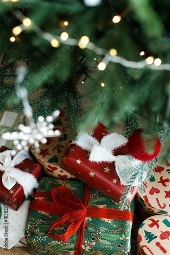 Christmas presents. Stylish christmas gift boxes with festive ribbons and ornaments under christmas tree with lights, top view. Merry Christmas! Holiday banner