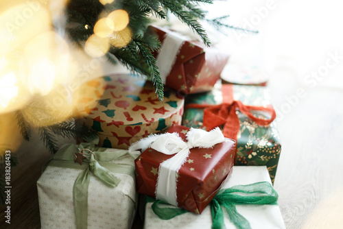 Christmas presents. Stylish christmas gift boxes with festive ribbons and ornaments under christmas tree with golden lights, top view. Merry Christmas! Holiday banner