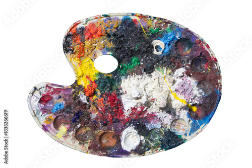 Paint pallet , isolated, old art materials , with oil paint ,  well used with remnants of lots of oil paints almost looking like a sculpted landscape that is seen from above.  