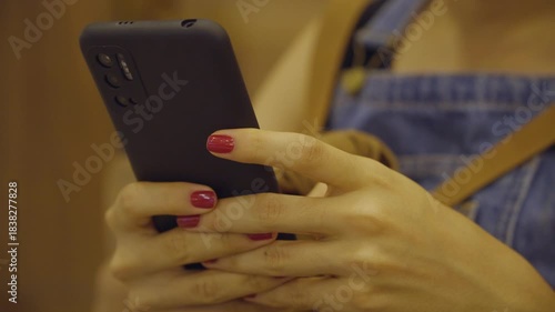 Close-up of a young woman's hands using a cell phone, scrolling